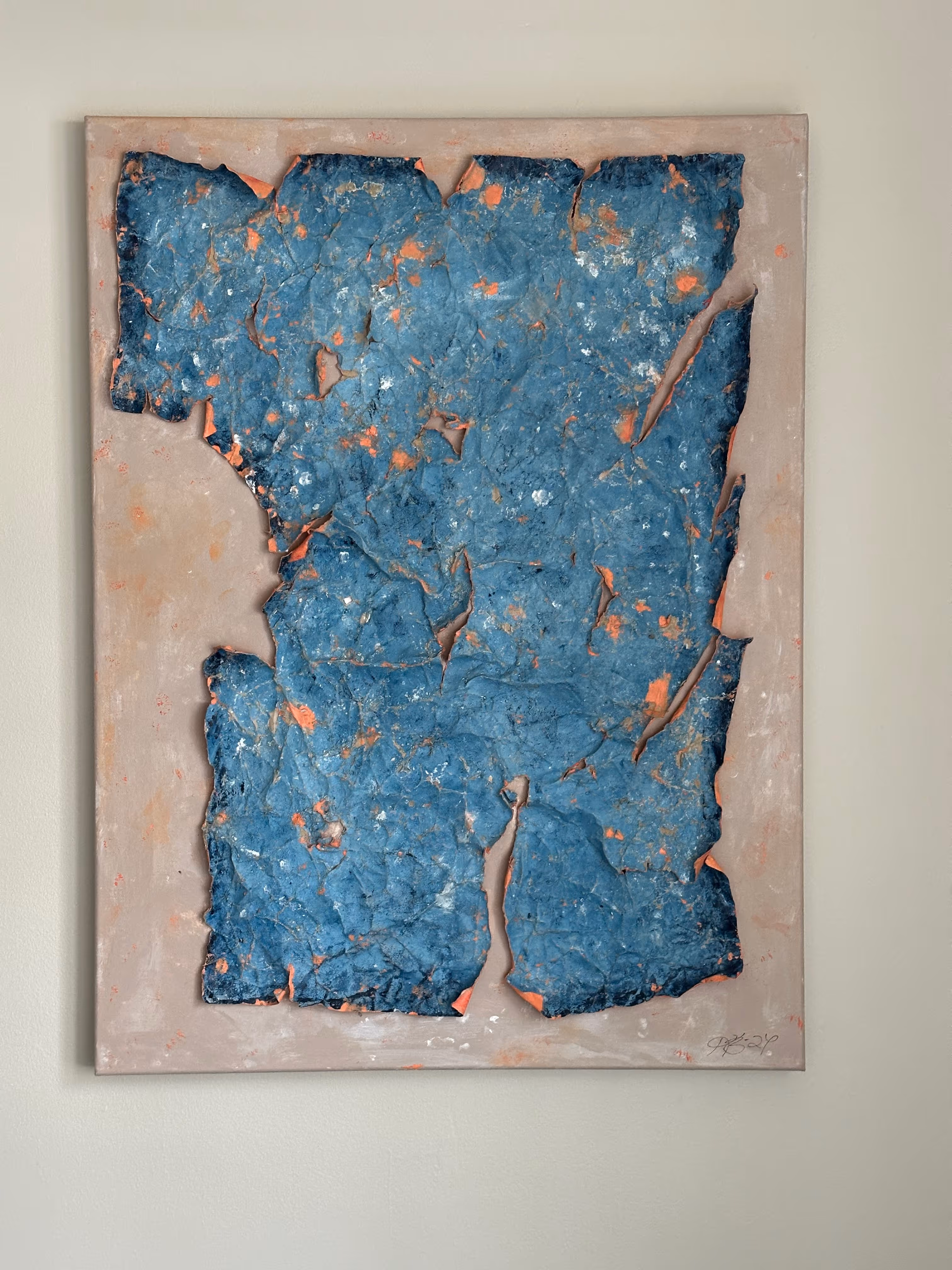 Abstract textured painting with a blue cracked surface peeling to reveal orange underneath on a beige background.