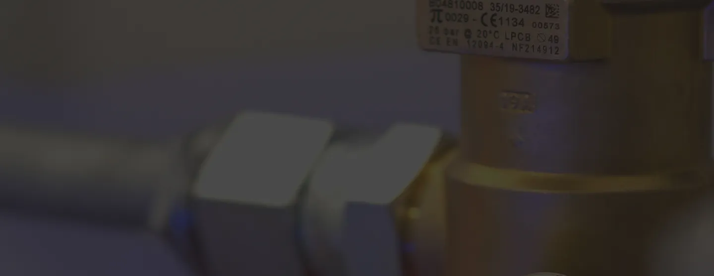 Detailní pohled na kovové průmyslové potrubí s maticovým spojem a označením parametrů.