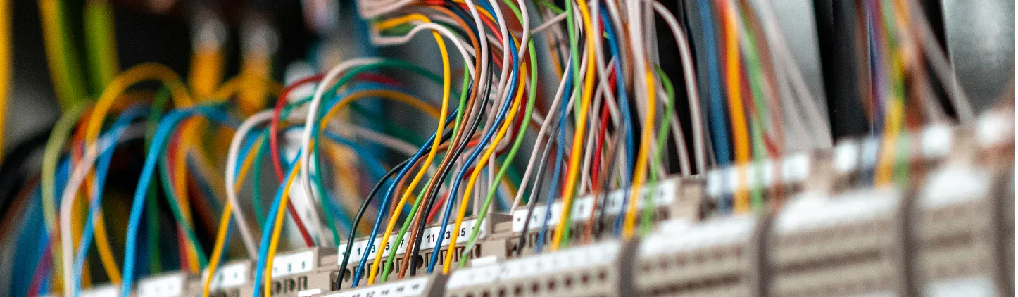 Barevné elektrické vodiče připojené k rozvodné desce s označením čísel.