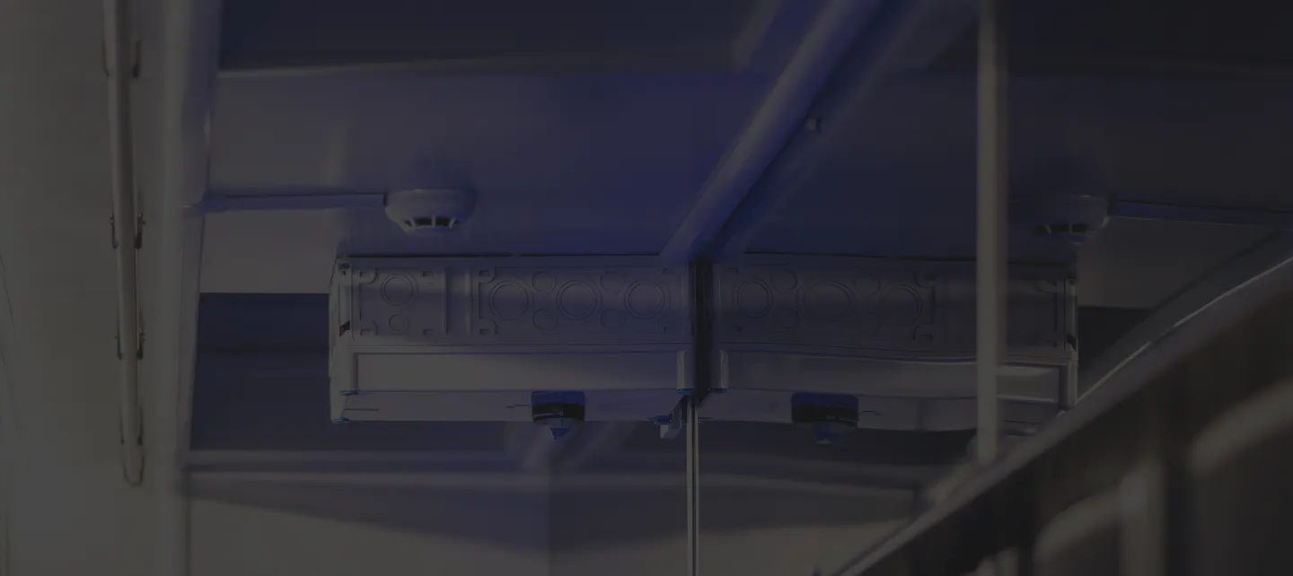 Detail útrob infrastruktury datacentra s metalickými trubkami a elektronickými zařízeními na stropě.