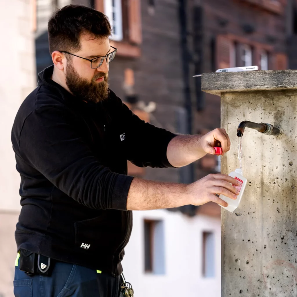 Un employé OIKEN prélève un échantillon d'eau potable d'une fontaine pour vérifier sa qualité