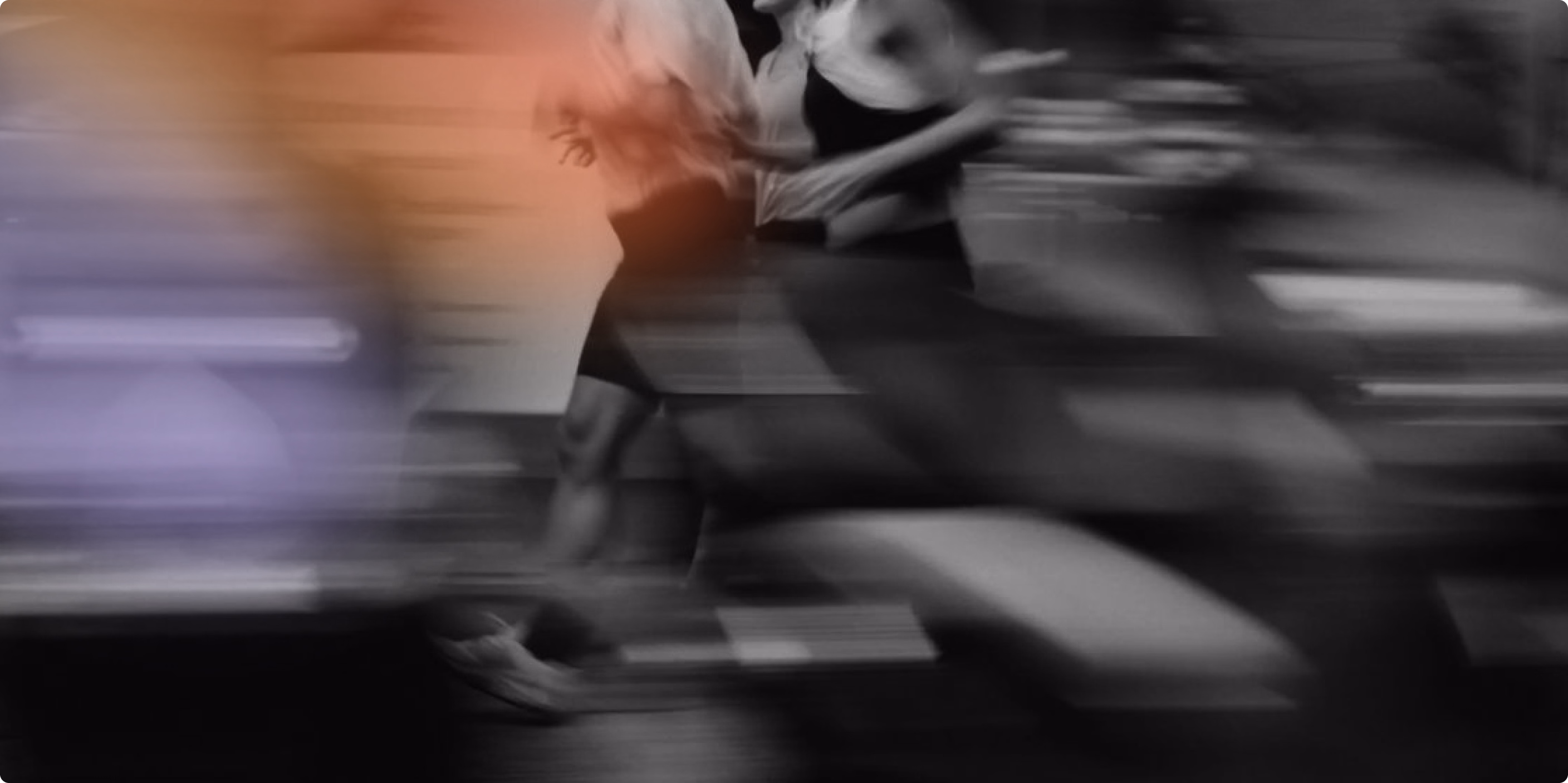 Blurred image of two women running side by side, showing motion and speed.