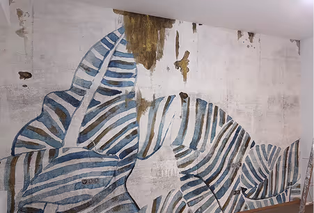 Großes Wandgemälde eines Zebras mit blauen und weißen Streifen auf unebener, leicht beschädigter Wand.