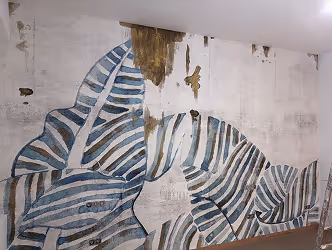 Große Wandmalerei mit abstrakten Blättern in Blau- und Brauntönen auf weißem Hintergrund.