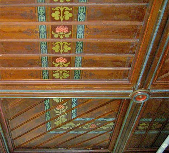 Holzdecke mit bemalten floralen Mustern und dekorativen Rahmen.