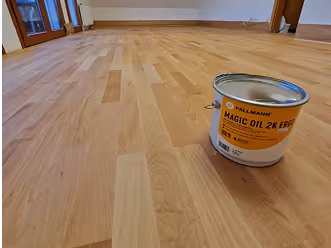 Eimer mit Pallmann Magic Oil 2K ERGO steht auf hellem, frisch geöltem Parkettboden in einem leeren Raum.