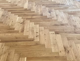 Holzboden mit Fischgrätmuster in verschiedenen Helligkeitsstufen.