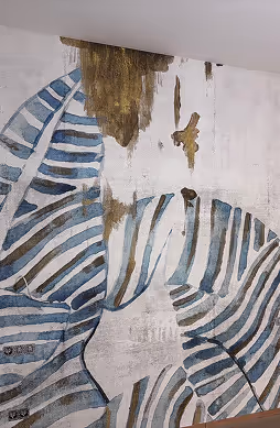 Wandmalerei mit blauen und weißen gestreiften Blättern und Wasserflecken an der Decke.