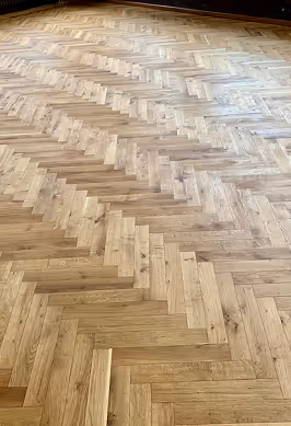 Holzparkettboden mit Fischgrätmuster in einem Raum mit natürlichem Licht.