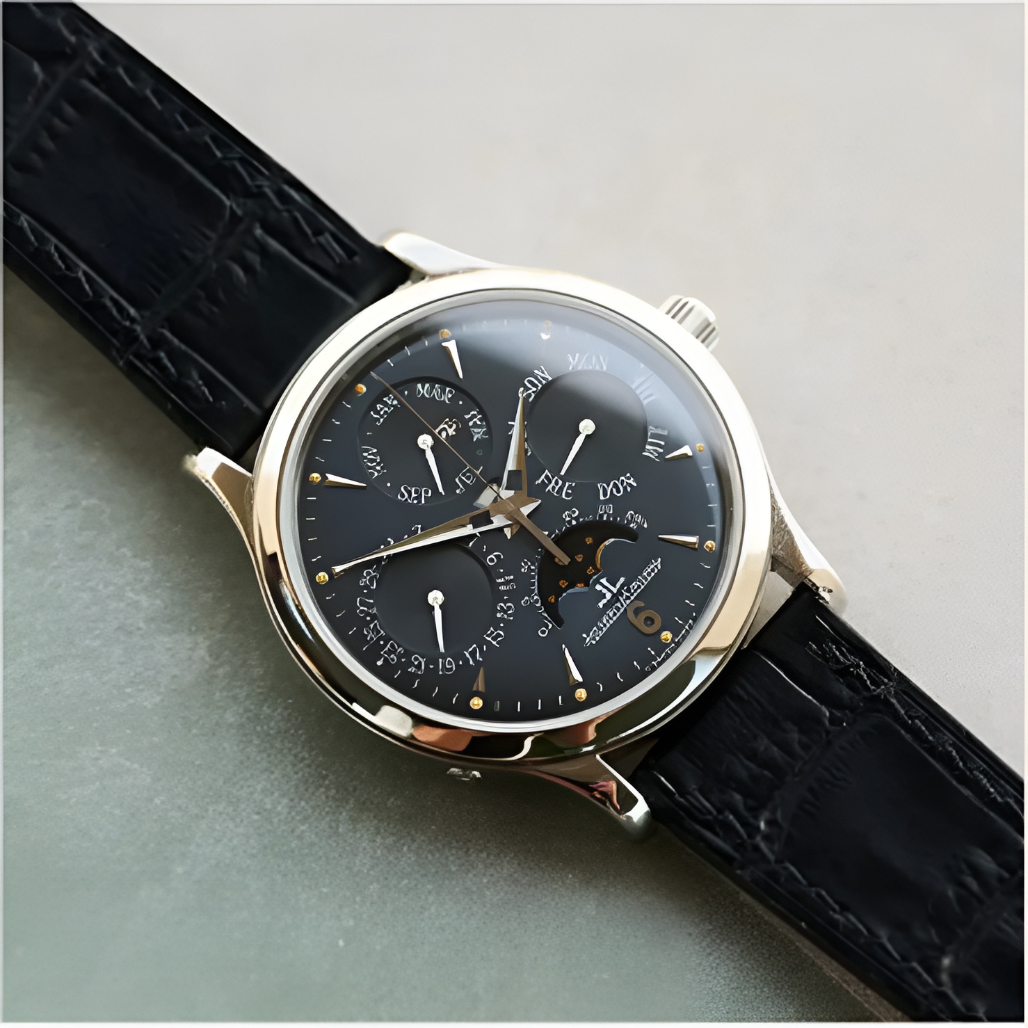 Close-up of a luxury wristwatch with a black leather strap and multiple dials on a black face, showing time and calendar features.