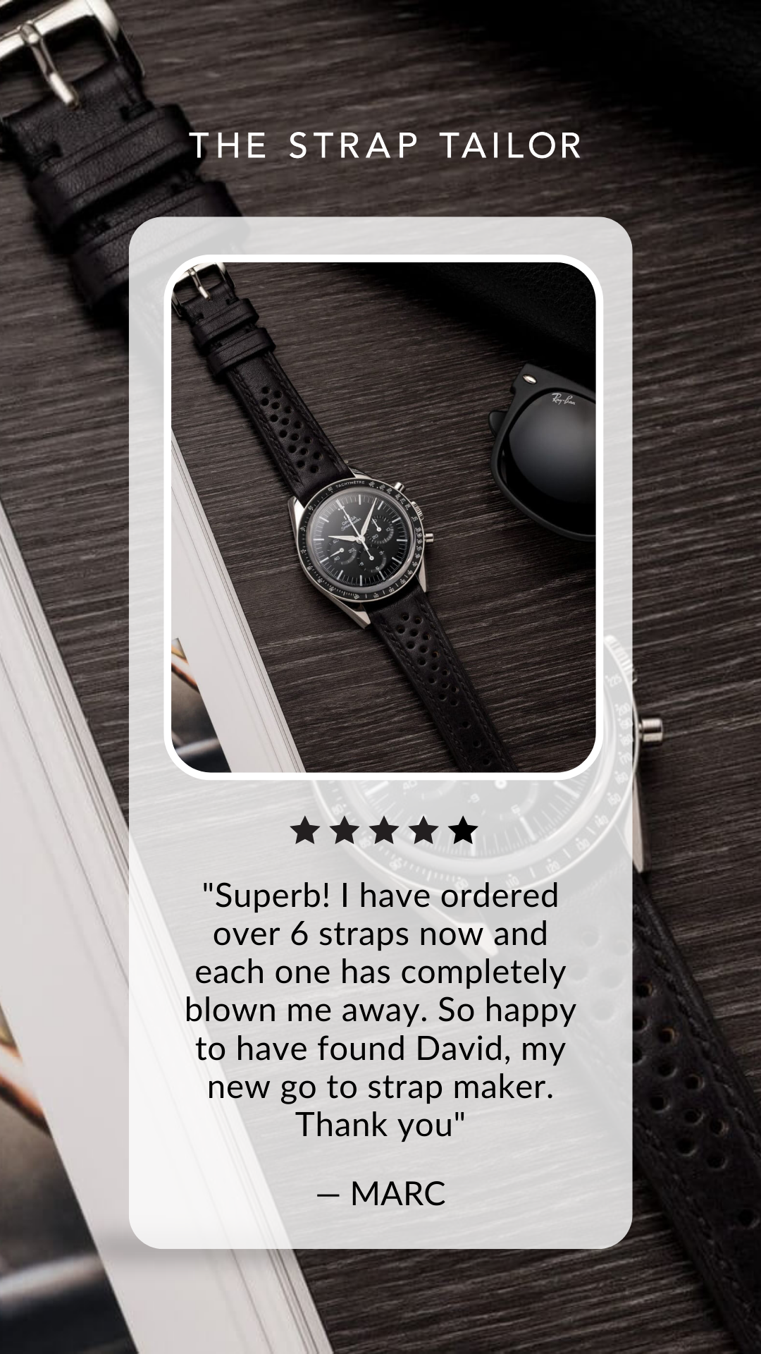 Black leather perforated watch strap on a black chronograph watch resting on a dark wooden surface next to black Ray-Ban sunglasses and an open book.