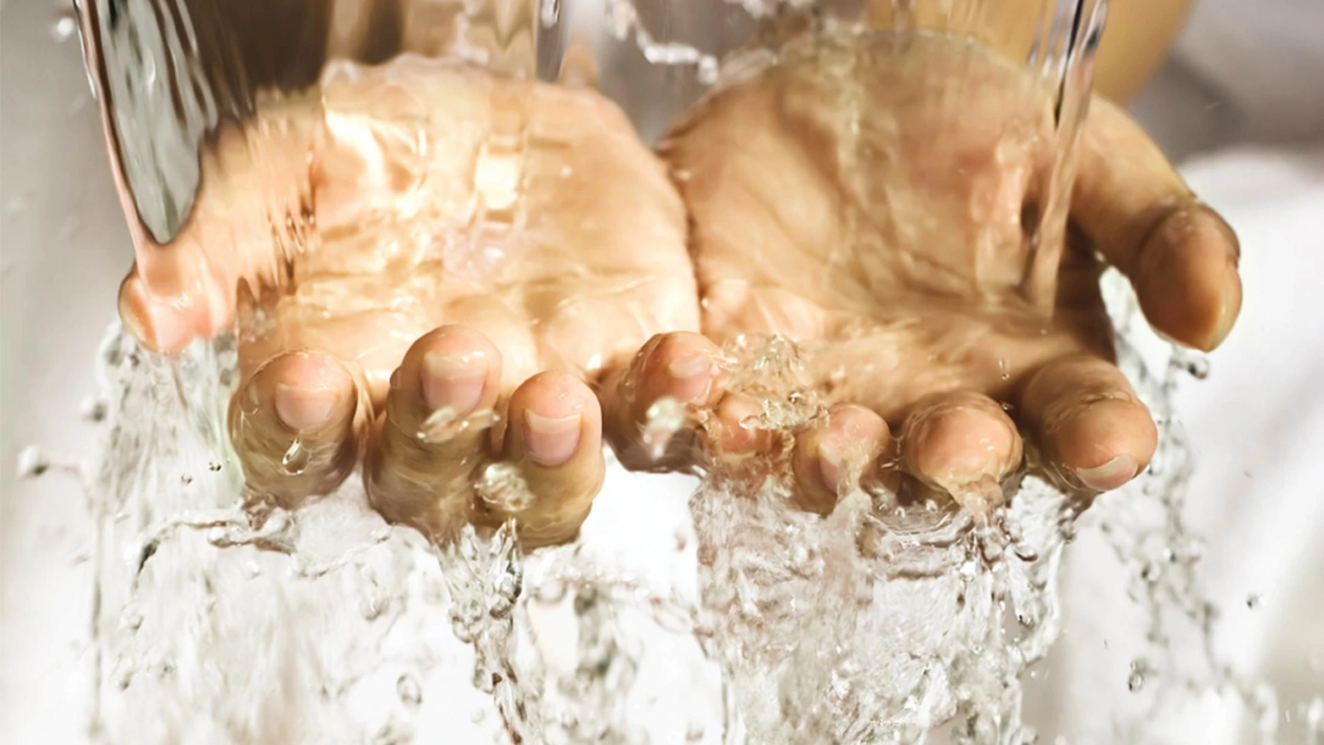 Hands being washed under running water as part of hygiene procedures.