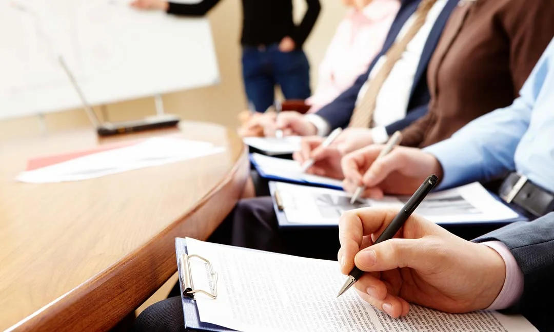 People in a classroom setting taking notes during a training presentation.