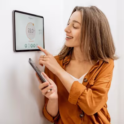 A mulher sorri ao utilizar a automação residencial para tornar sua rotina mais fácil e eficiente, apreciando os benefícios de uma casa inteligente.