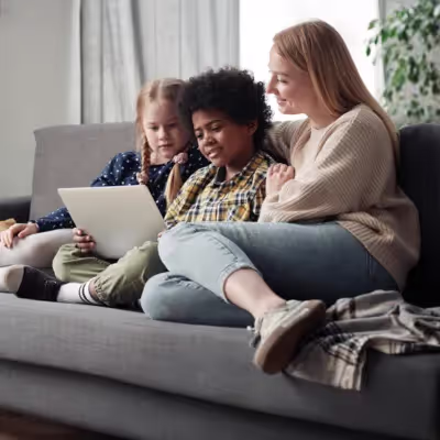 Mãe e filhos assistindo Globoplay juntos no sofá.