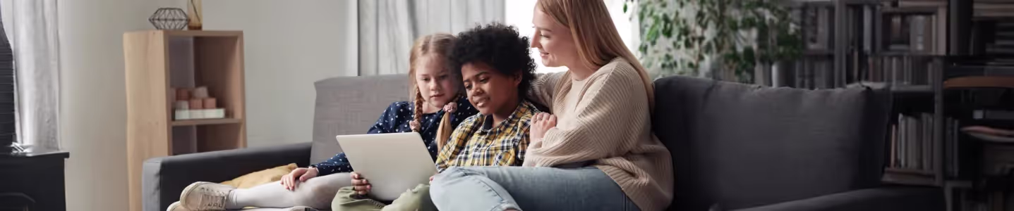 Mãe assistindo Globoplay com os filhos no sofá da sala.