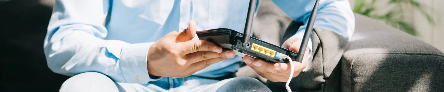 Homem ajustando o roteador para melhorar o sinal Wi-Fi.