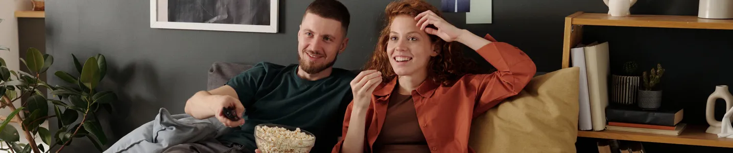 Casal feliz assistindo TV juntos em casa.
