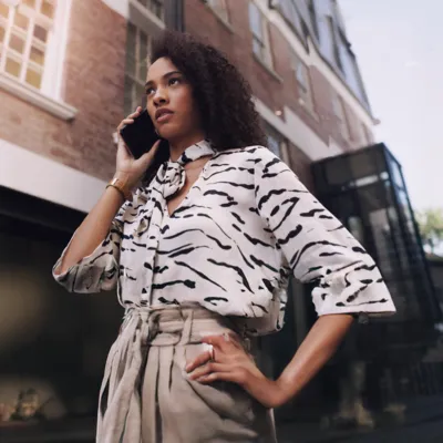 Mulher recebendo ligação de telemarketing em casa, com expressão atenta.