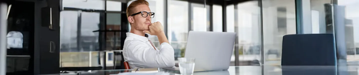 Homem pensativo em frente ao notebook.