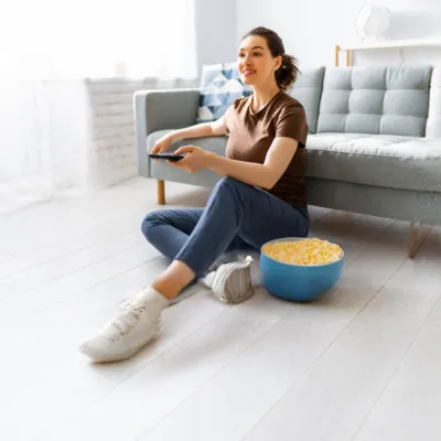 Mulher no chão da sala conectando a TV à internet.