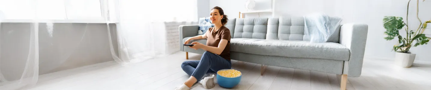 Mulher sentada no chão da sala, conectando internet à TV.