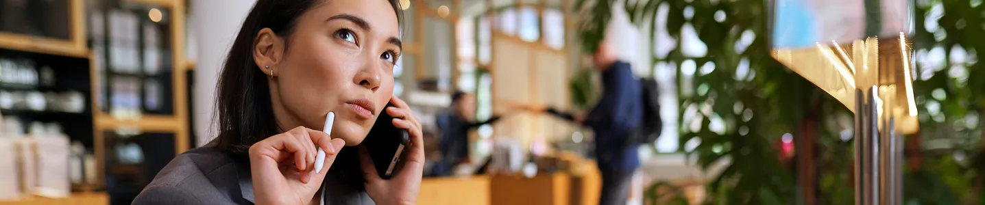 Uma jovem mulher está com dúvidas sobre como fazer uma ligação a cobrar, buscando informações ou instruções sobre o procedimento para realizar a chamada.