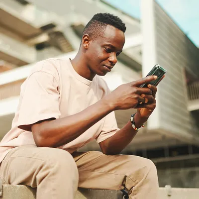 Pessoa mexendo no celular enquanto está sentada.