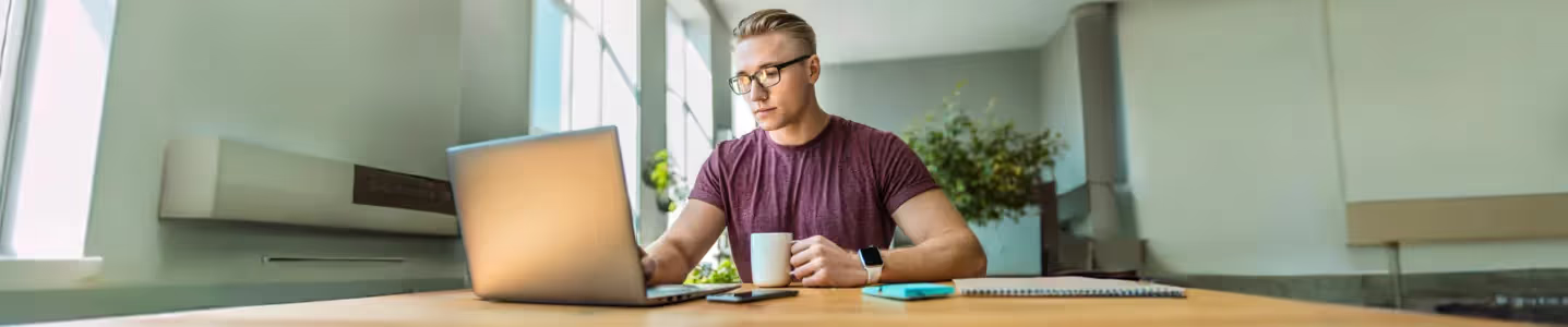 Trabalhador executivo sentado no escritório de casa com uma xícara de café e trabalhando.