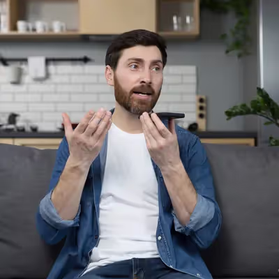 Pessoa interagindo com a Siri pelo celular na sala.