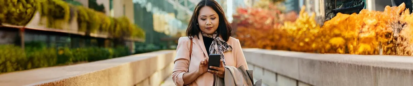 Uma mulher está consultando em seu celular os códigos DDD de cada estado, buscando informações sobre os prefixos telefônicos regionais.