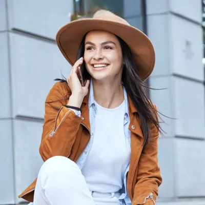 Conversa ao celular por mulher de chapéu na escada.