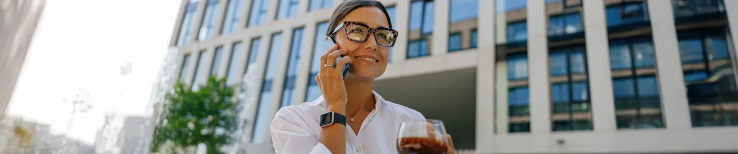 Mulher tomando café e falando ao smartphone.