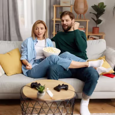 Casal assistindo Discovery Plus na sala de estar, relaxando com documentários.