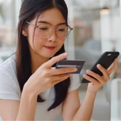 Com agilidade, a mulher efetua o pagamento da sua fatura de internet pelo celular, evidenciando a comodidade de realizar transações financeiras de forma instantânea e acessível.