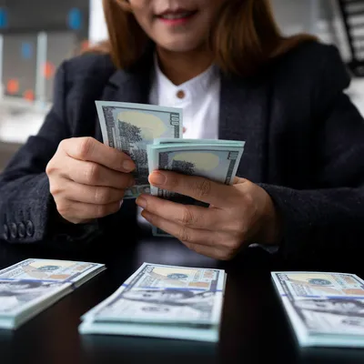 Uma jovem mulher está contando o dinheiro que ganhou online, evidenciando sua realização financeira através de suas atividades na internet.