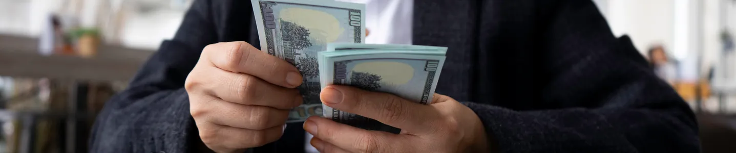 Uma jovem mulher está contando o dinheiro que ganhou online, demonstrando satisfação ao ver os resultados de seu trabalho e esforço na internet.