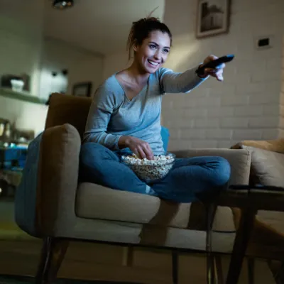 Mulher relaxa no sofá da sala assistindo Max.