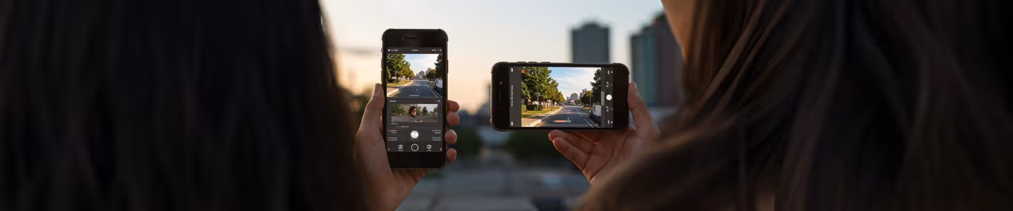 Duas pessoas tirando foto com celular ao ar livre