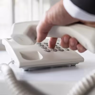 Com habilidade, a mão masculina segura o telefone de fio e discando um número, demonstrando a destreza de uma era anterior das telecomunicações.