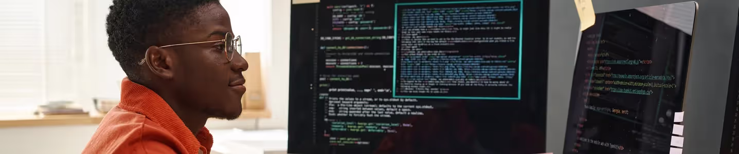 Um jovem engenheiro de TI, sério e vestindo uma camiseta laranja inteligente, está concentrado enquanto examina dados codificados, demonstrando sua habilidade em analisar e interpretar informações digitais.