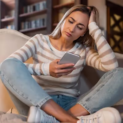 Mulher preocupada ao notar que seu celular exibe a mensagem "Não Registrado na Rede".