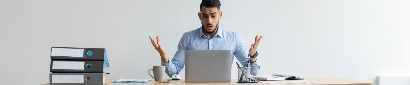 Um homem abre as mãos expressando confusão diante do laptop, pois percebe que seu computador está sem internet. O gesto reflete a frustração diante da interrupção na conexão, buscando soluções para restabelecer a comunicação online.