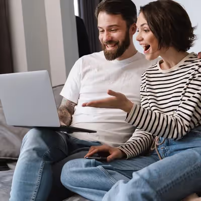 O jovem casal está extremamente satisfeito ao usar o serviço Oi Fibra Start em seu notebook, desfrutando de uma conexão rápida e estável para todas as suas necessidades de internet.