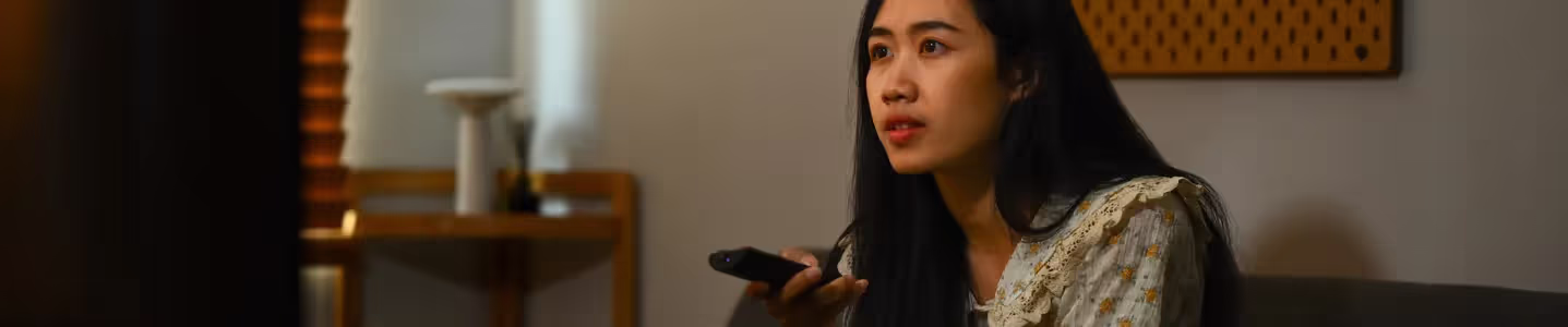 Com total envolvimento, uma jovem garota está entretida com a Oi TV Livre, explorando a variedade de conteúdos e desfrutando de uma experiência televisiva envolvente.