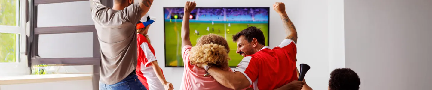 Grupo de amigos assistindo futebol no Premiere, torcendo animadamente.