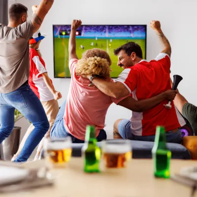 Grupo de amigos assistindo futebol no Premiere, celebrando cada lance.