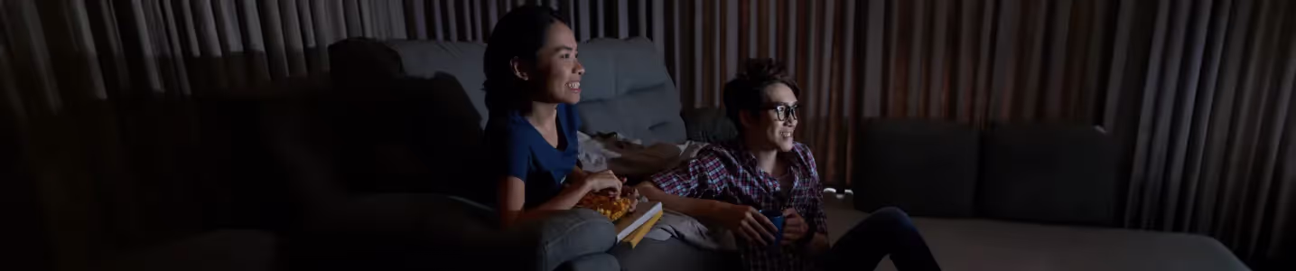 Casal assistindo série na TV juntos no sofá.