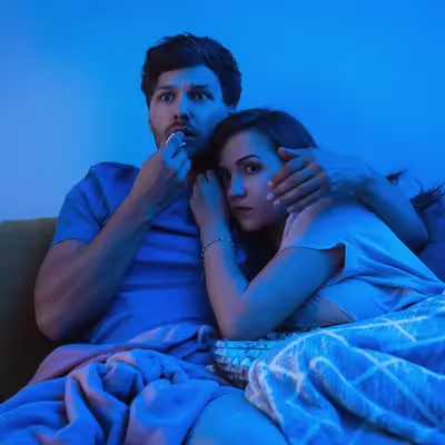 Casal curtindo um filme de suspense na televisão.