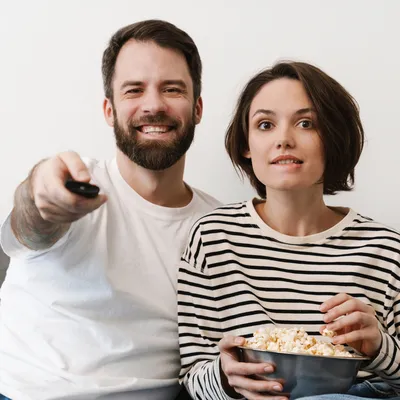 Um casal de jovens compartilha risadas enquanto assiste à televisão.